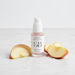 Close-up of the serum bottle with apple slices, water droplets, and marble surface, highlighting fresh ingredients and hydration